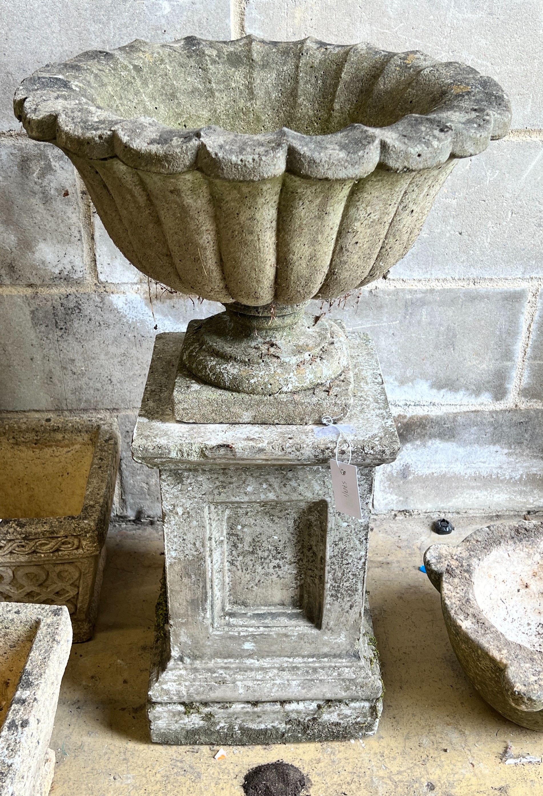 A reconstituted stone campana garden urn on square plinth, diameter 49cm, height 82cm